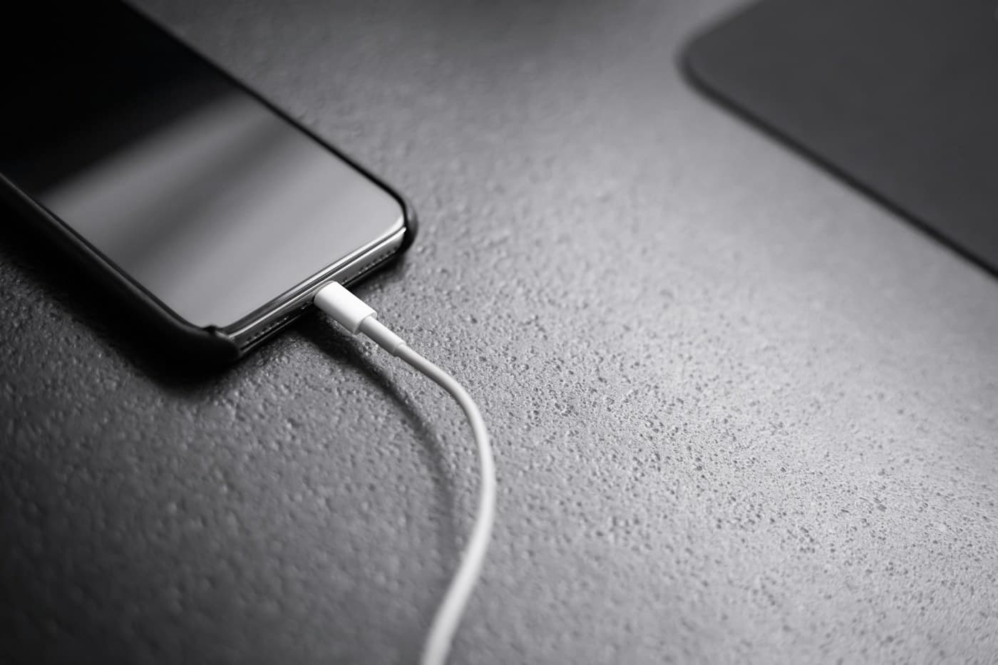 Teléfono con cable de carga sobre superficie oscura